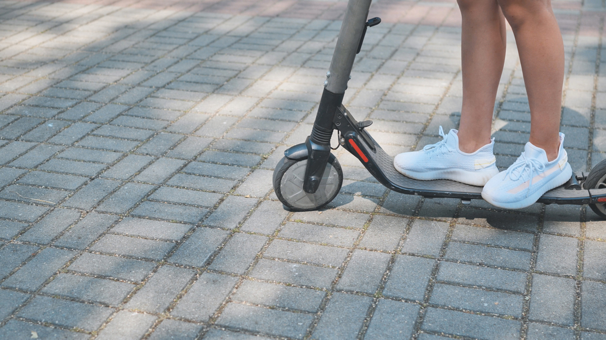 En person står på en elsparkcykel på en gata