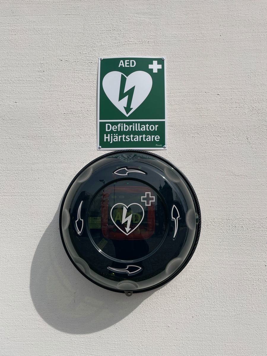 En hjärtstartare sitter på en vit husvägg