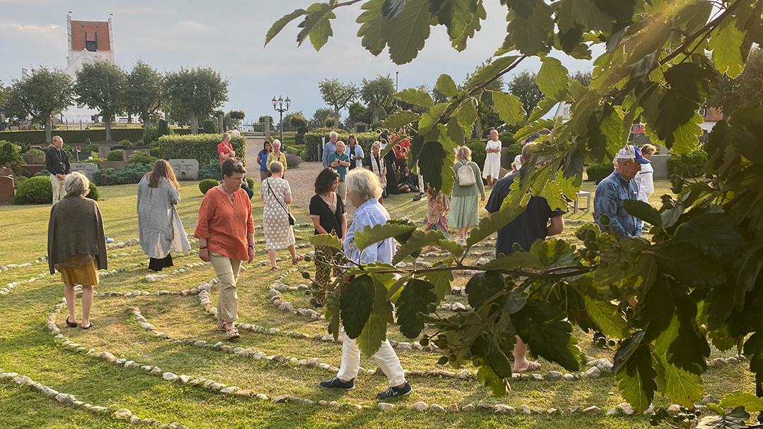 Människor går i en labyrint av stenar som är utlagda på marken. 