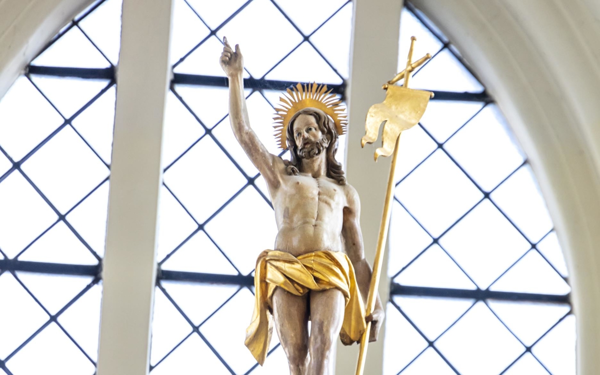 Kristusstaty med guldkrona, gyllene höftskynke och fana.