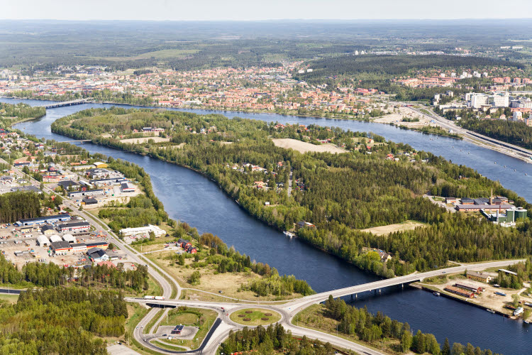 Flygbild över landskap med stad, grönska och bro över en älv.