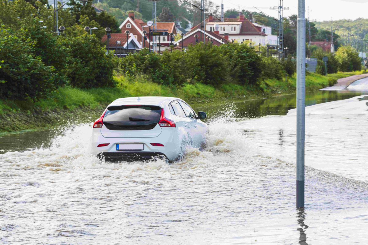 En bil kör på översvämmad väg 