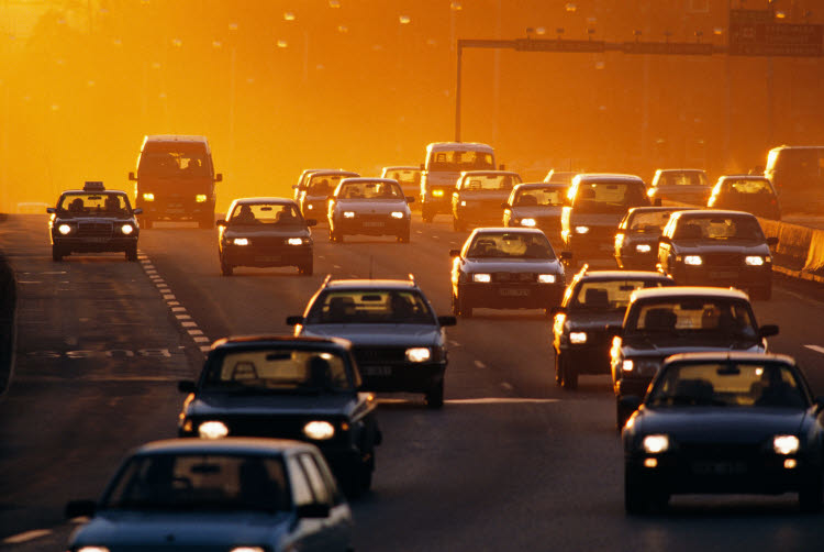 Bilar på flerfilig motorväg med solen i bakgrunden