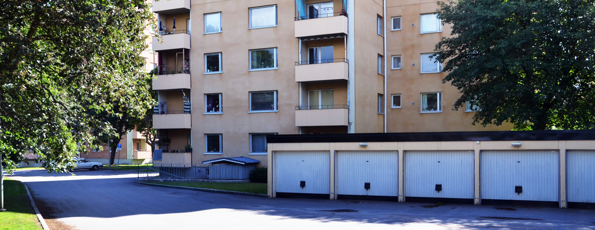 Garagelänga framför ett hyreshus. Illustrerar Skatteverkets beslut om att lägga moms på förhyrda parkeringar.