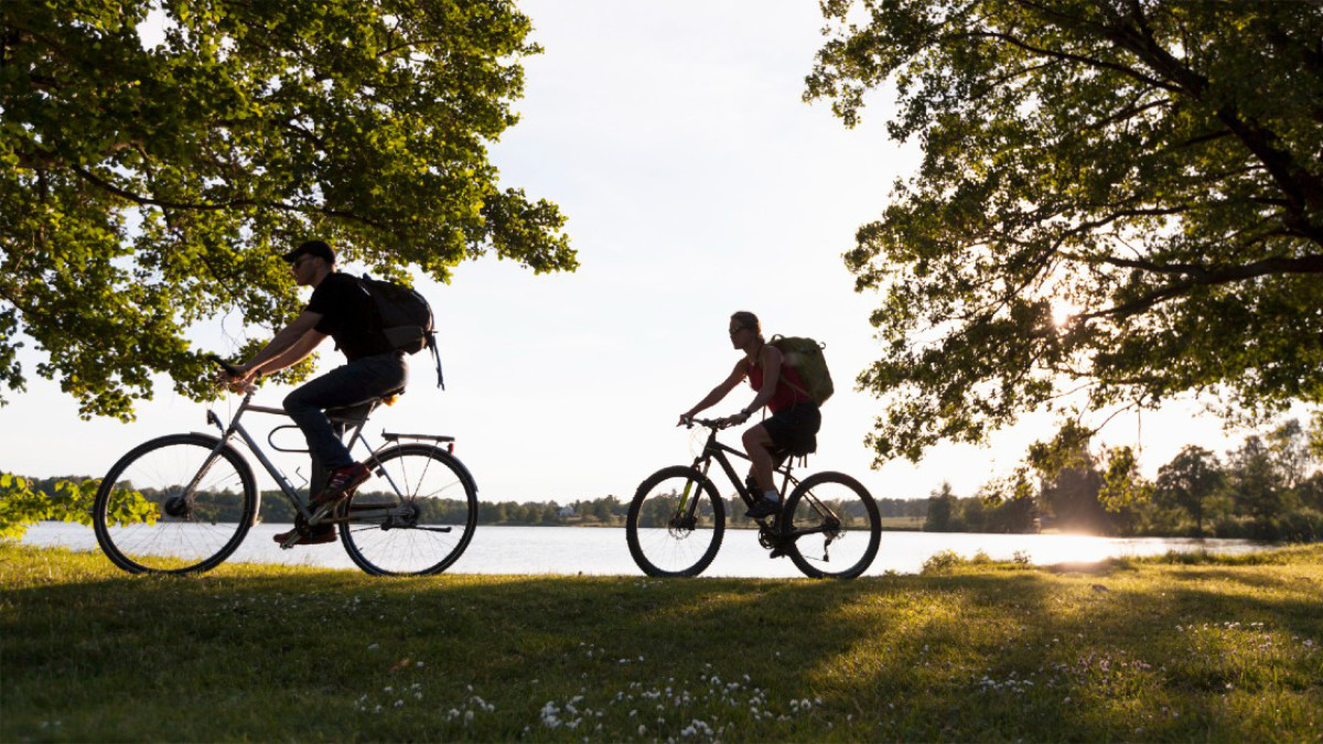 Två cyklister vid sjö i kvällssol