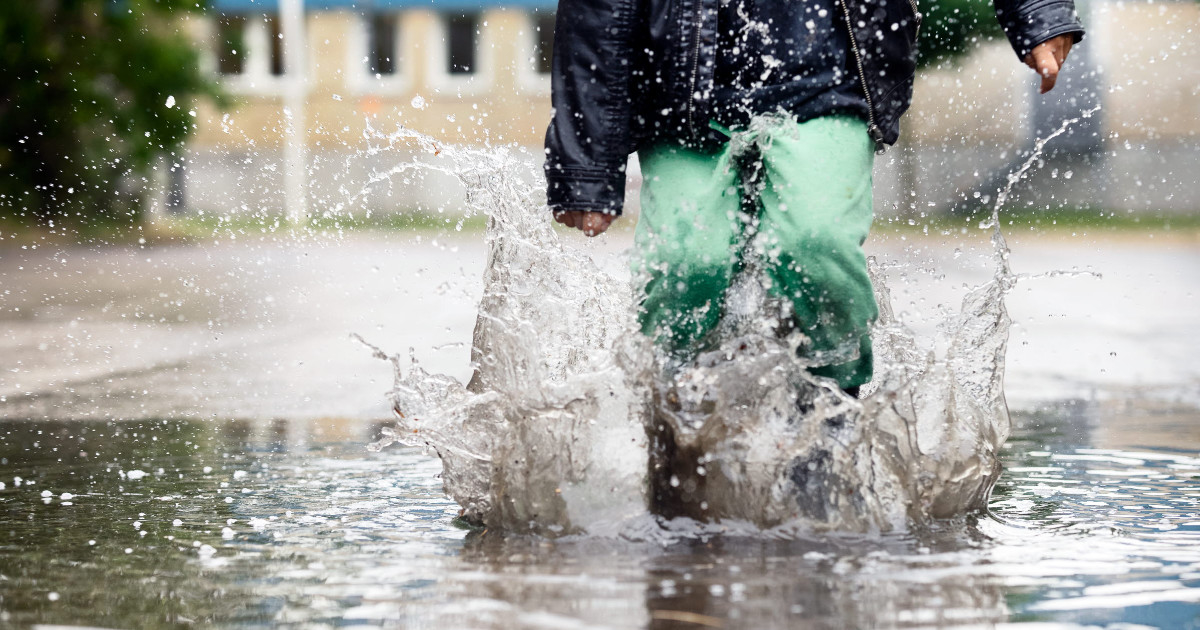 barn hoppar i stor vattenpöl