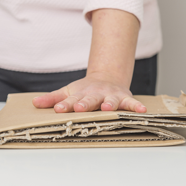 Bild på hand som plattar ihop förpackningar