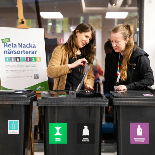 Bild på två kvinnor som visar upp tre avfallskärl