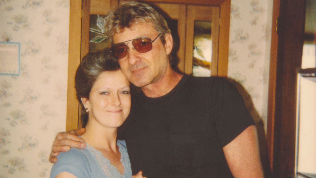 En man och en kvinna som håller om varandra och tittar in i kameran och ler.